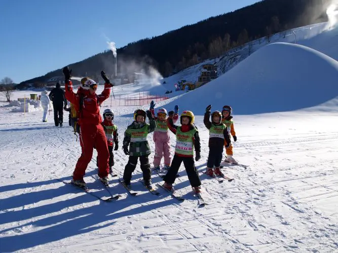 Skilehrer jubelt mit einer Kindergruppe