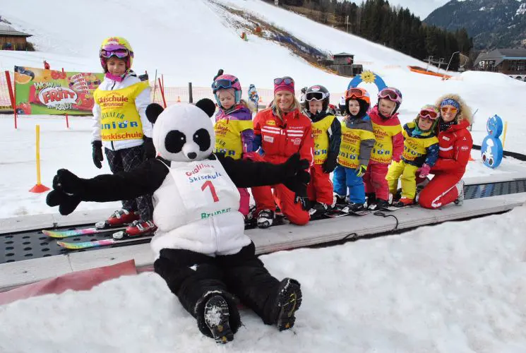 Panda-Maskottchen mit Kindern im Skikurs